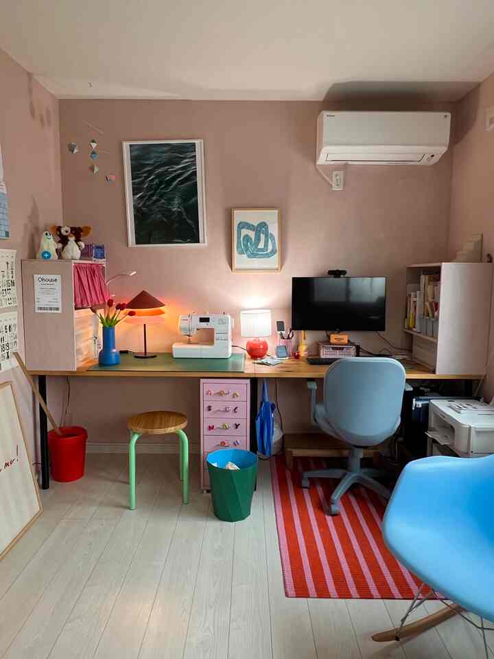 Pink-toned walls with colorful furniture in a home office and workspace featuring warm lighting and practical storage