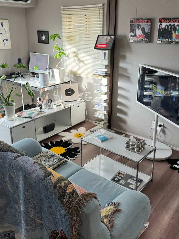 Modern white-tone living room and home office featuring desk, sofa, and floral rugs in a clean interior