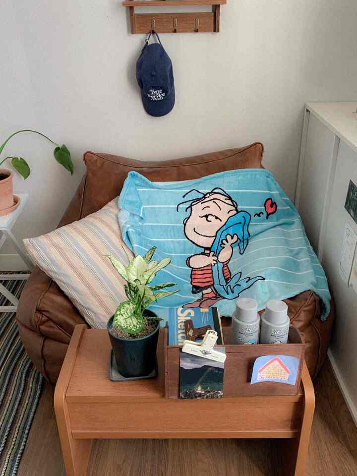 ブラウンの木目調が印象的なリビングコーナー、ビーズクッションと可愛らしいブルーのブランケットが配置された雰囲気のある空間