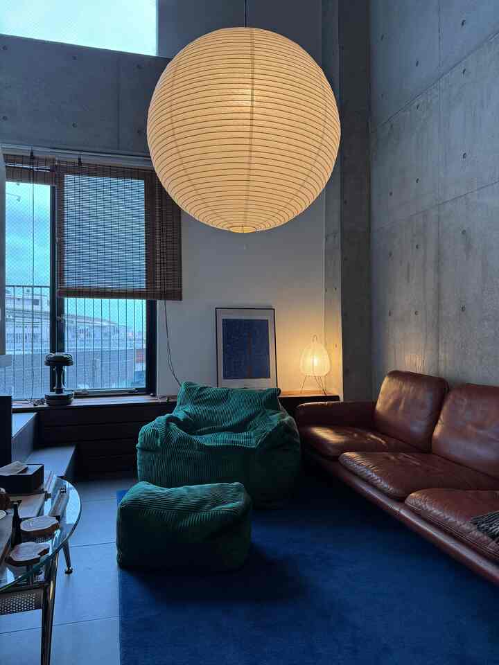 落ち着いたブルーとブラウンのリビング、ビーズクッションとレザーソファが配置されたヴィンテージなミッドセンチュリーモダンな印象的な空間