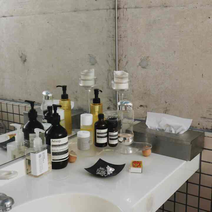 白を基調としたバスルームの洗面台、さまざまな化粧品とディフューザーが整然と配置された空間