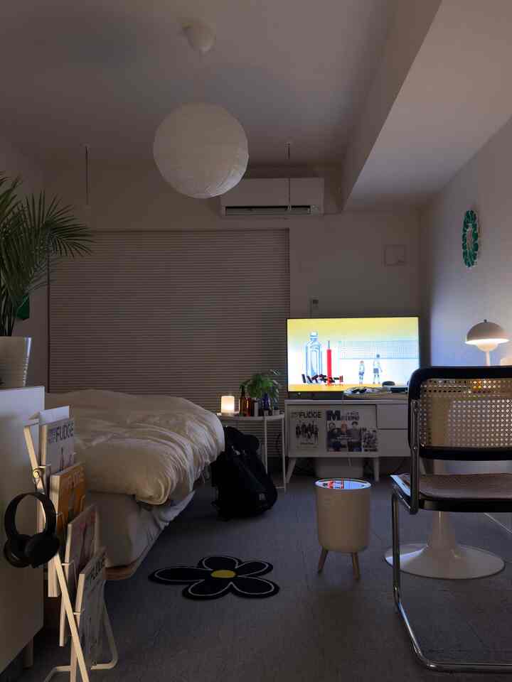 白とグレーのトーンの一人暮らし用寝室、ベッドと机の上にテレビが配置された落ち着いた空間