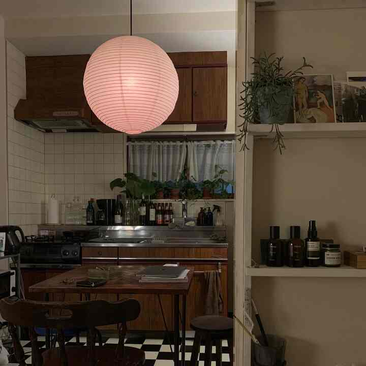 温かみのあるオレンジ色調のアパートのキッチンスペース、木製ダイニングテーブルとペンダントライトが配置された雰囲気のあるインテリア