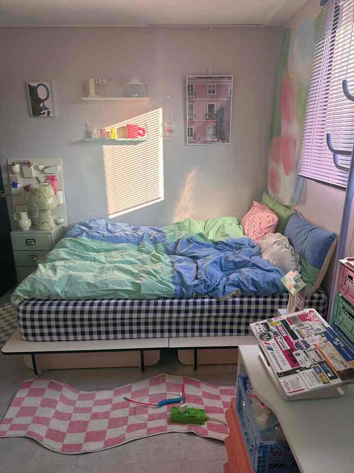 柔らかいパステル調のブルーとグリーンの寝室、チェック柄ベッドフレームと可愛らしい小物が配置された落ち着いた空間