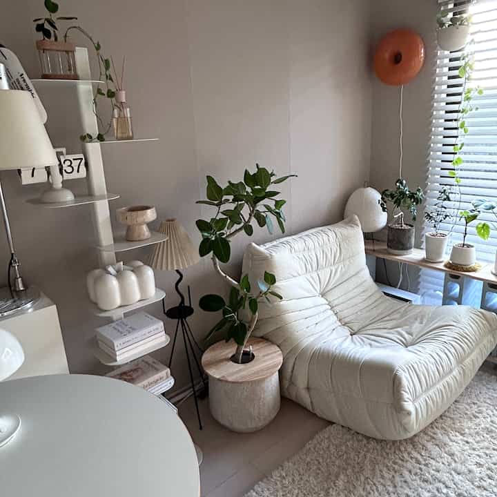 Natural modern living room featuring a white sofa bed and green plants with a cozy, bright atmosphere