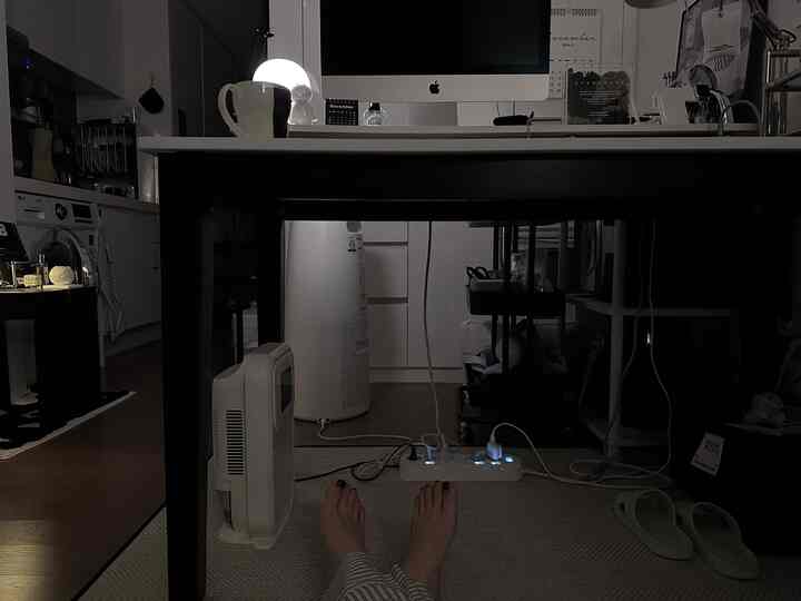 暗いトーンのコンパクトなキッチンとモダンなホームオフィス空間、白い家電と黒い机が配置されたインテリア
