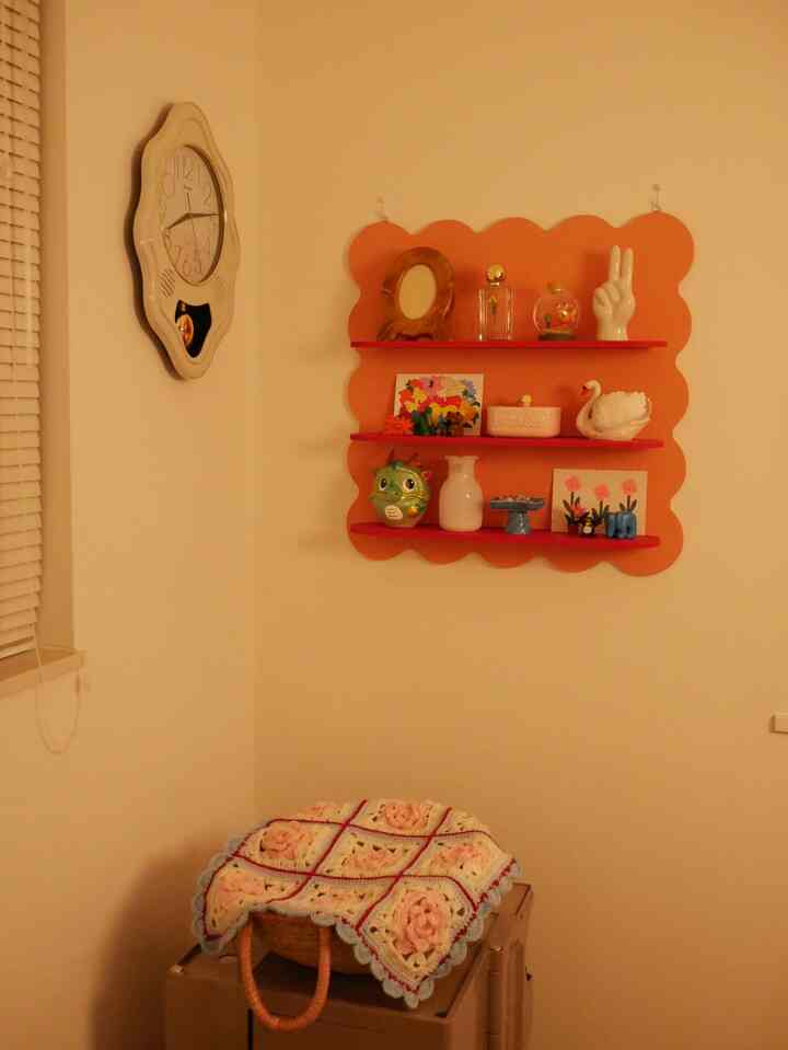 Cozy small room corner with warm beige tones, featuring orange scalloped wall shelves displaying various decorative objects
