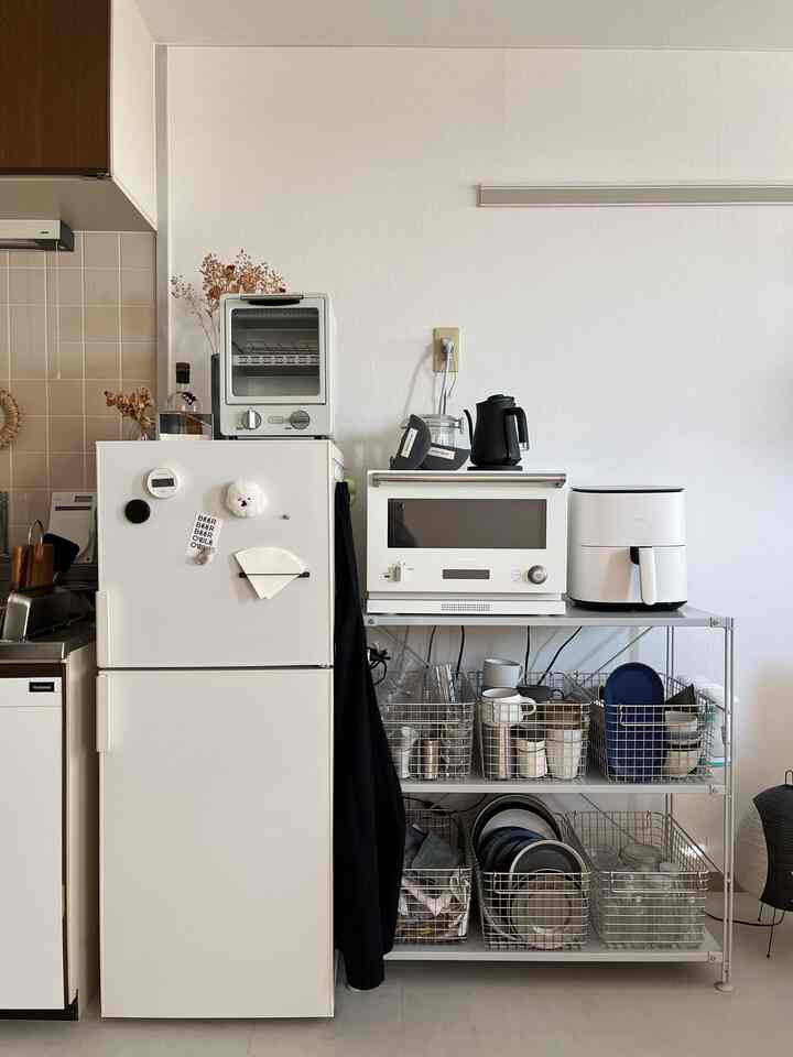 白を基調としたキッチン、無印良品の収納バスケットとバルミューダの電気オーブンがシンプルに配置された空間