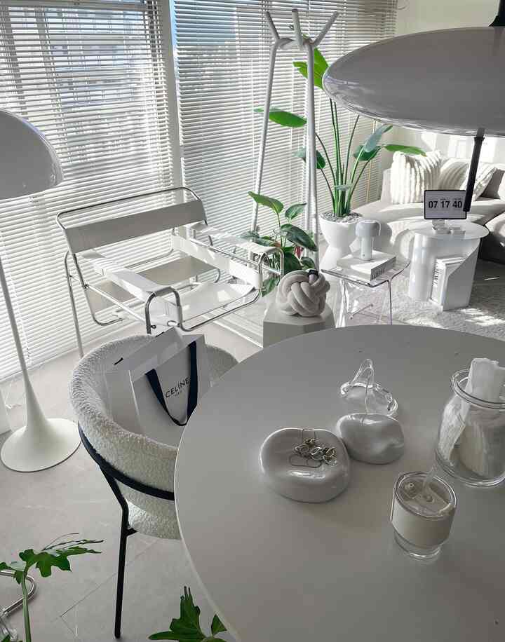 白とナチュラルトーンのリビング、シンプルな家具とフロアランプ、植物が配された印象的なインテリア