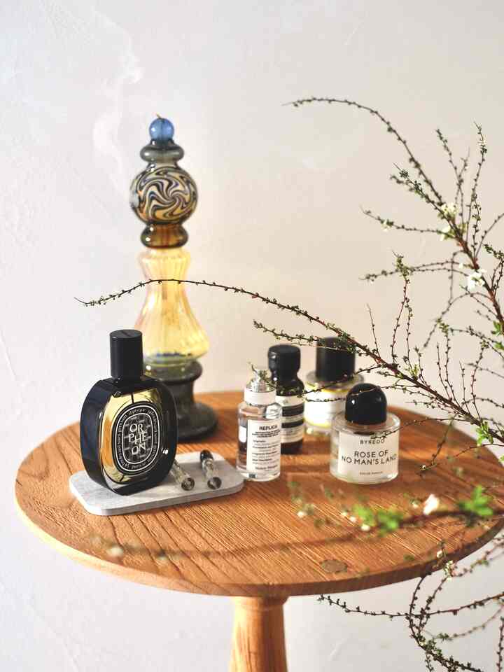 Wood tone round table featuring perfume bottles and diffuser in a neat entrance space