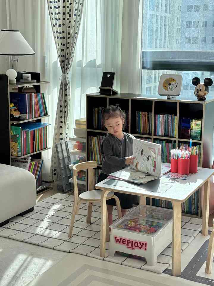 白とナチュラル色調の子供部屋、机で読書をする子供がいる教育的で整理された空間