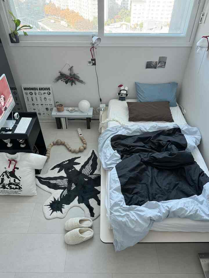 ホワイトとモノトーンの色調が調和した一人用寝室、ミニマルな寝具とクリスマス飾りが配置されたすっきりした空間