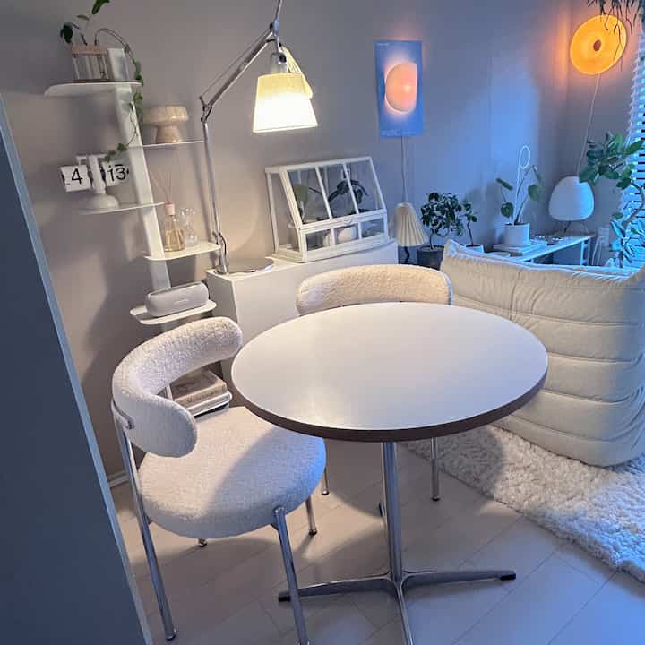 白とシルバーのトーンのリビングダイニング、丸いダイニングテーブルと柔らかな曲線のチェアが配置されたシンプルで明るいインテリア