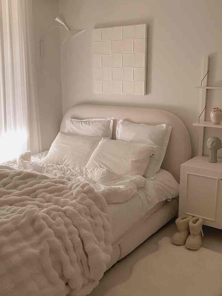 柔らかなナチュラルカラーとホワイトトーンの寝室、丸みのあるベッドフレームとふわふわのブランケットが配置された雰囲気のあるインテリア