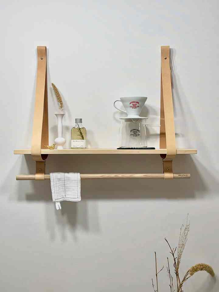 ナチュラルカラーのキッチン空間、レザーのストラップで吊られた木製の棚にコーヒー器具とキッチンタオルが配置された清潔感のあるインテリア