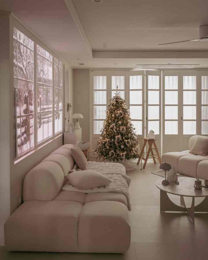 White-toned living room featuring a Christmas tree and two sofas with a minimalist interior design