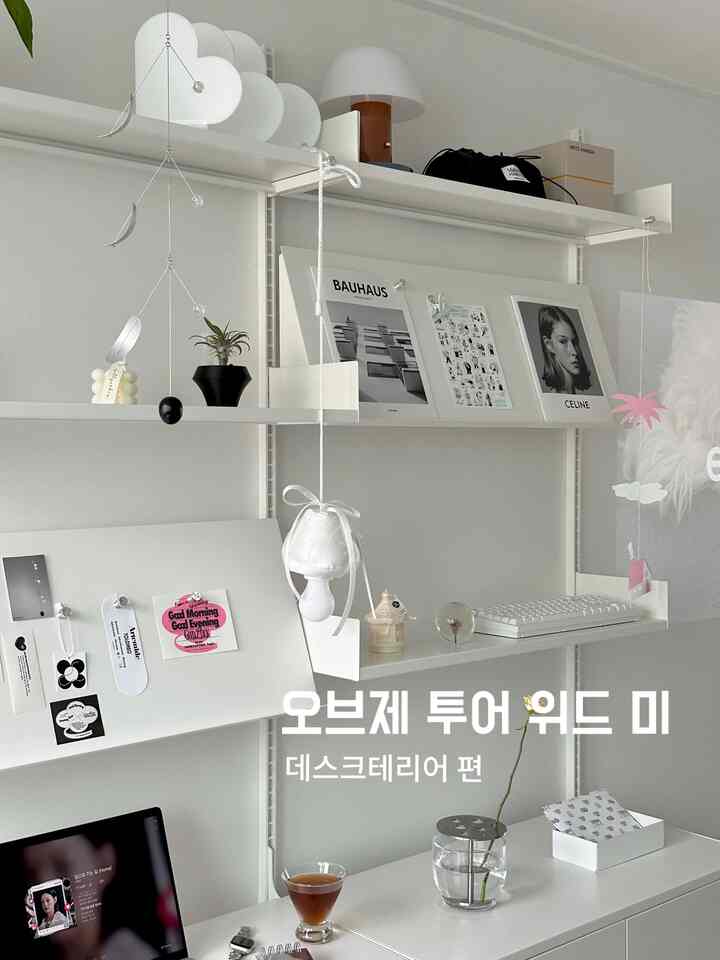 白を基調とした棚とデスクが配置されたモダンで清潔感のあるホームオフィス、様々なオブジェと照明が映えるインテリア