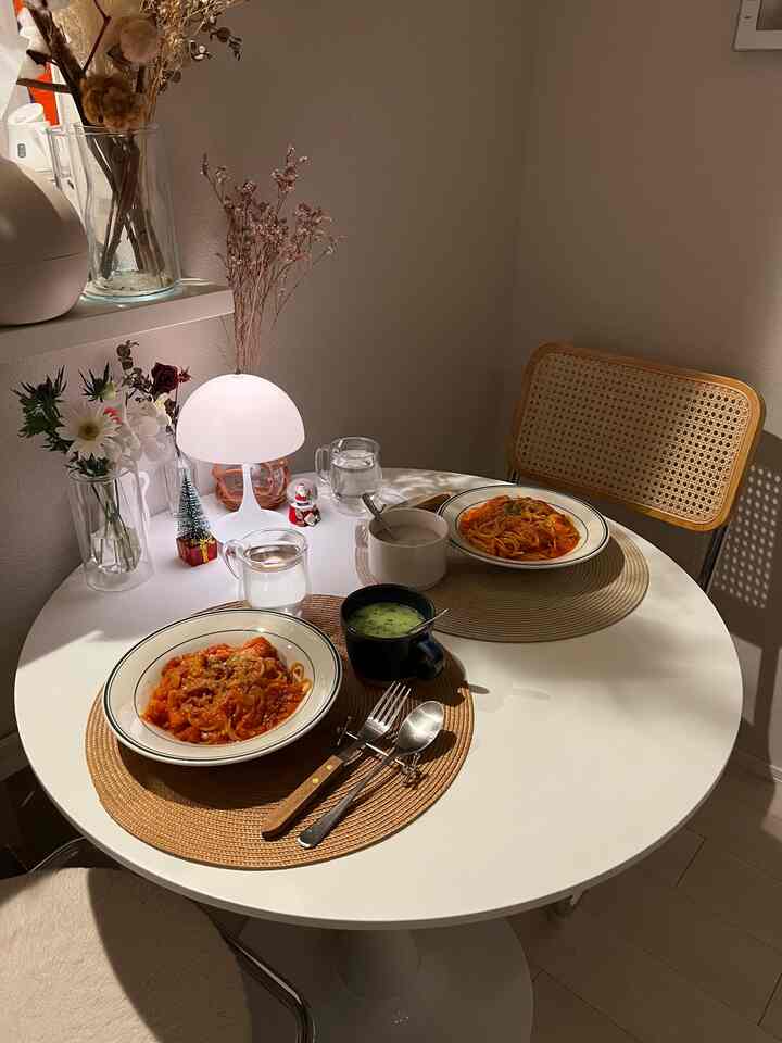 白とナチュラルカラーのダイニング空間、円形テーブルとラタンチェアが配置された雰囲気あるおうちデートの空間