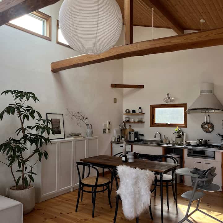 ナチュラルな木目調とホワイトトーンの北欧スタイルキッチンダイニング、ペーパーペンダントライトとダイニングチェアが配された温かみのある空間