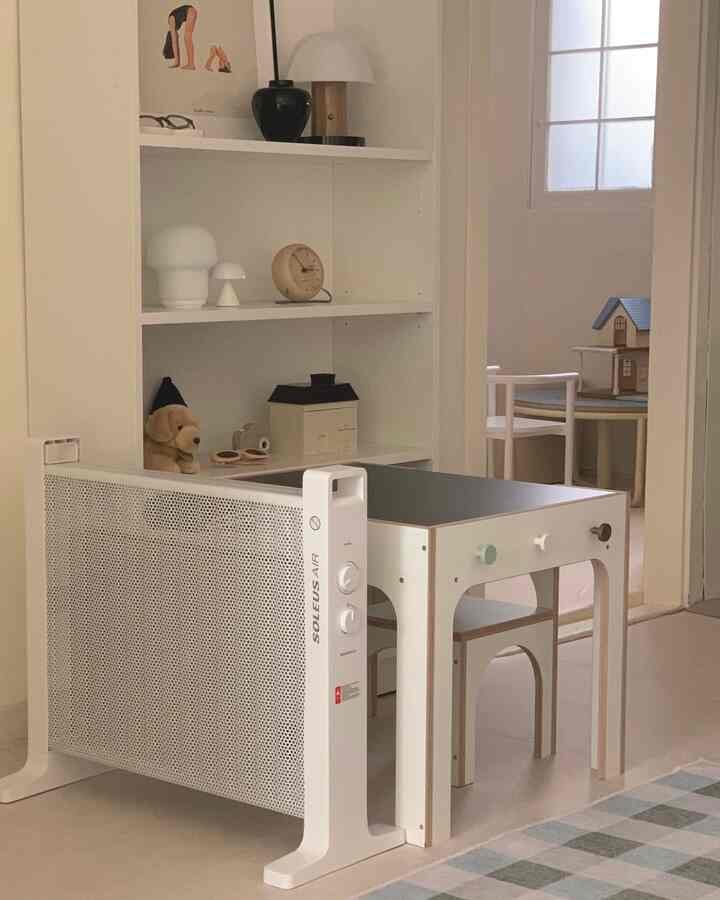 白とベージュのトーンの子供部屋、子供用デスクと椅子、本棚が配置されたミニマルで雰囲気のあるインテリア