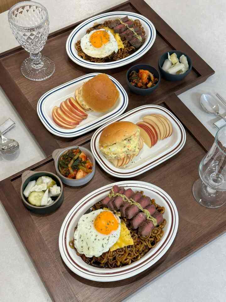Cozy home cooking scene with natural brown wood tone dining table featuring oval and rectangular plates with plated homemade meal