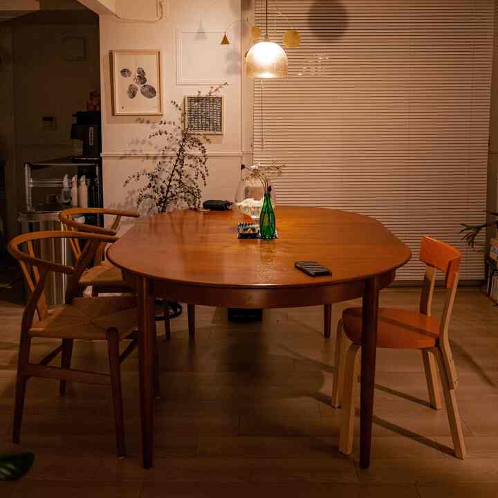 暖かい木目調のダイニング、ラウンドテーブルと北欧スタイルの椅子が配置された落ち着いた雰囲気の空間