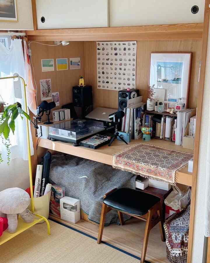 Warm brown-toned workspace featuring a wooden desk and stool, compactly arranged with audio equipment and books