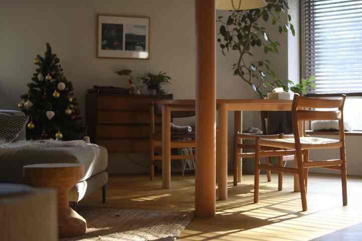 暖かいライトブラウンの色調のダイニング兼リビングルーム、クリスマスツリーとブラインドが配置された雰囲気のある空間