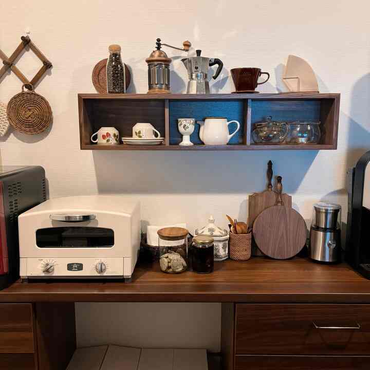 Brown wood tones and gray appliances form a cozy kitchen featuring coffee tools and cutting boards neatly arranged in a home cafe style