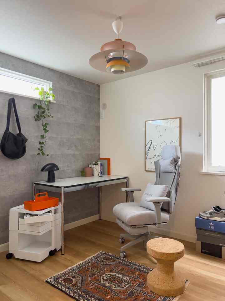 White and gray toned home office featuring functional desk, office chair, and cork stool in a clean workspace