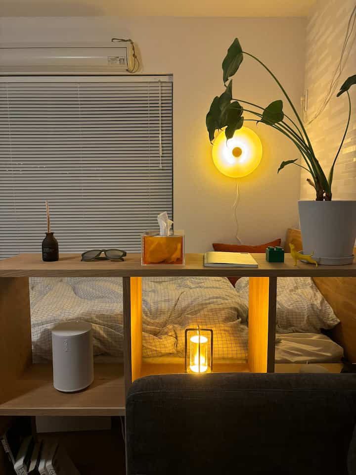 ナチュラルカラーの寝室、木製の棚と壁照明が配された雰囲気のあるインテリア