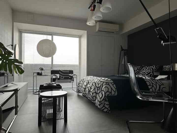 黒と白の色調の寝室、柄の寝具とモダンな家具が配置されたシンプルで清潔感のあるインテリア