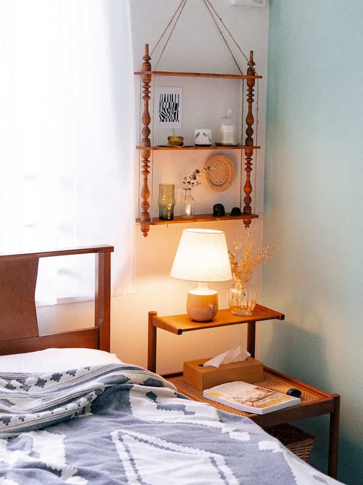 A warm wood-toned natural color bedroom featuring a bed, nightstand, and table lamp creating a cozy atmosphere