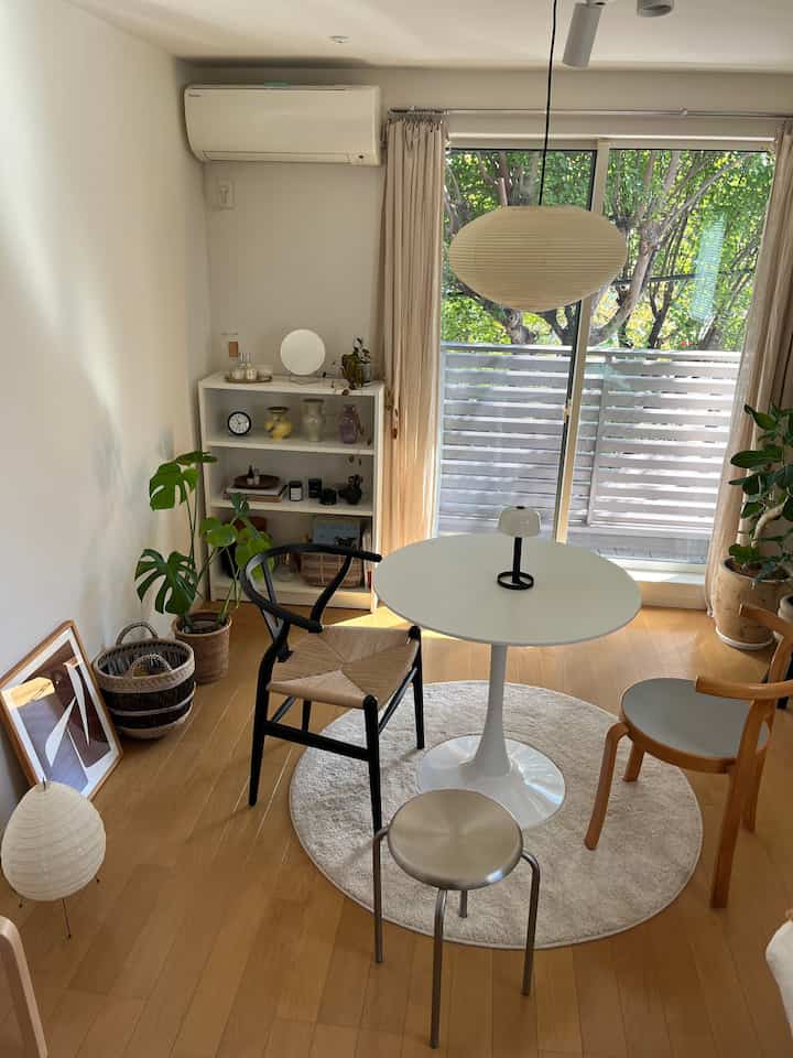 Wood tone and white 1K studio dining area for single household, featuring natural cafe style interior with plants and cozy atmosphere