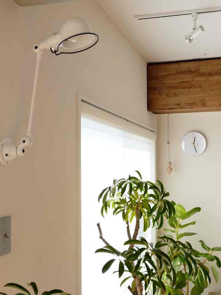 White-tone walls and ceiling featuring a wall clock with yellow second hand and wall lamp in a simple, natural interior space