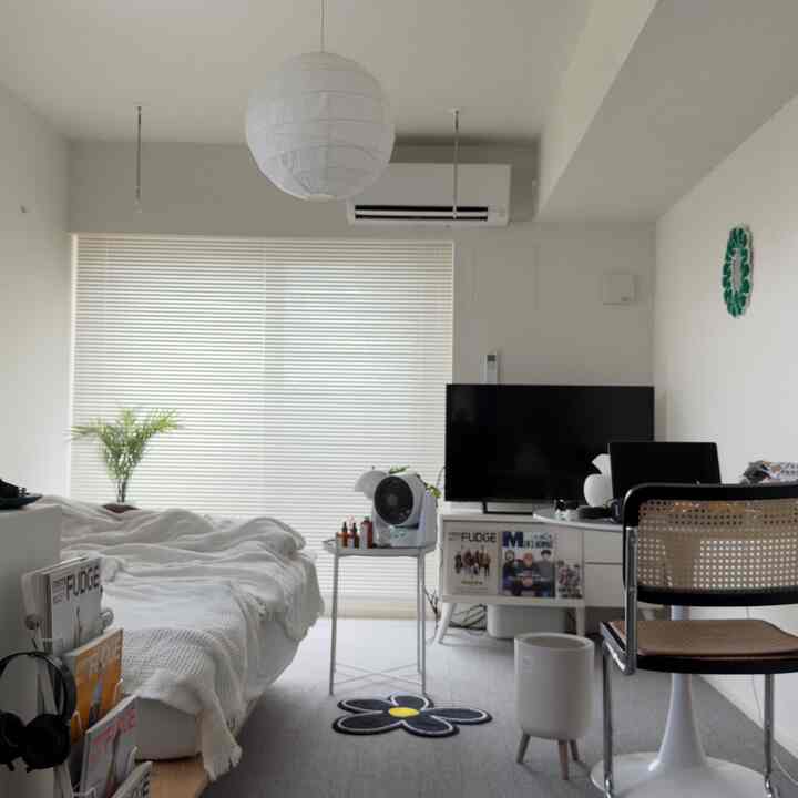 白を基調としたワンルームの寝室、デスクとオフィスチェアが配置されたシンプルでコンパクトな空間