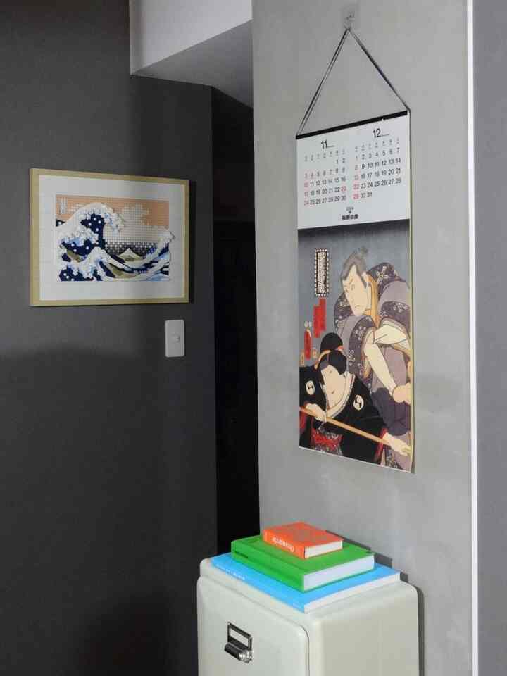 グレーの壁に日本の伝統的な美術作品が配置された、落ち着いた一人暮らしの1LDK空間