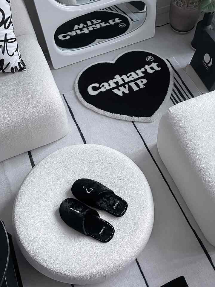 White and black toned balcony space featuring textured sofas, round stool, and heart-shaped rug creating a minimal vibe