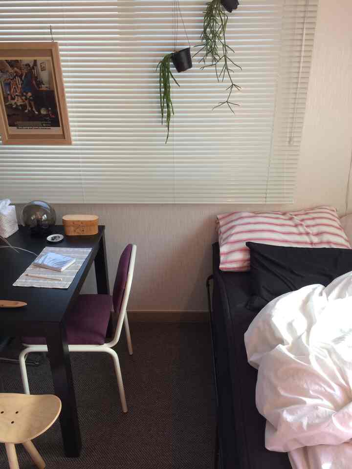 白と黒のトーンのワンルーム、ベッドとデスクがコンパクトに配置された清潔感のある印象的な空間