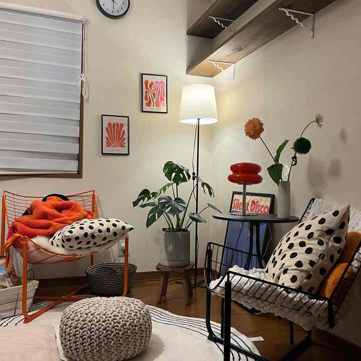 Living room in white and natural tones featuring orange armchairs, plants, and warm lighting for cozy atmosphere