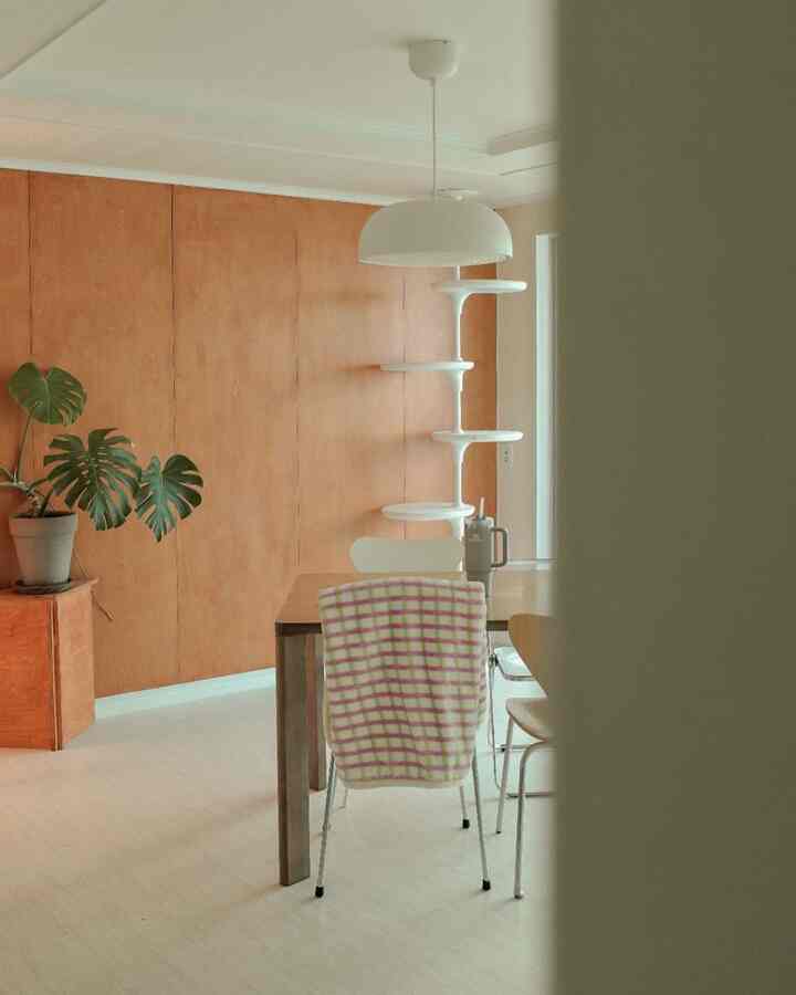 木目調壁と白い床のダイニング、ダイニングテーブルとキャットタワーが配置されたナチュラルな雰囲気のインテリア