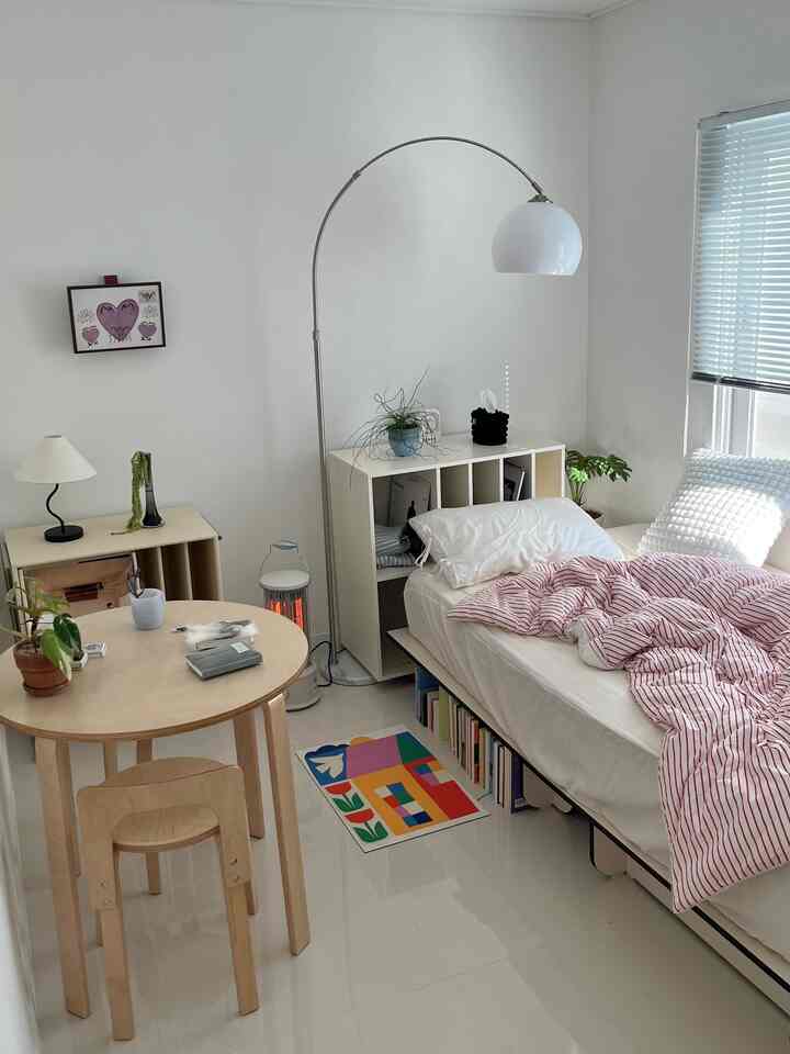 A natural modern bedroom in white and beige tones featuring a wooden table and bed with a cozy atmosphere