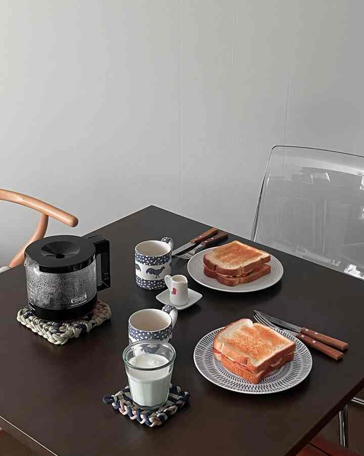 ブラウン調のダイニング、透明な椅子と木製の取っ手のカトラリーが配置された雰囲気のあるおうちカフェ空間