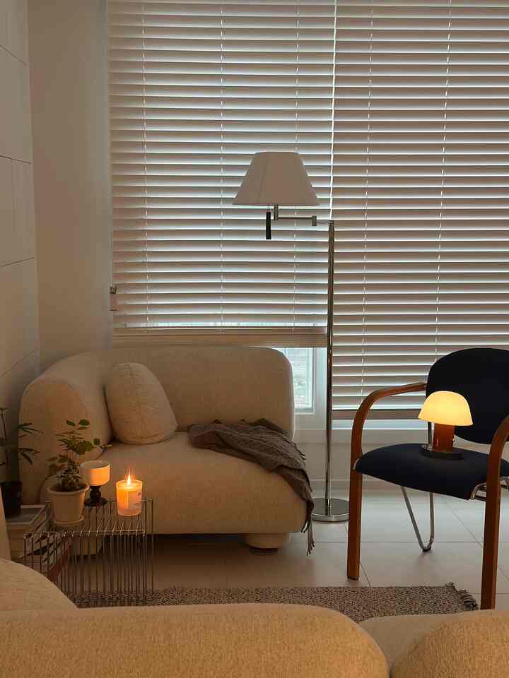 Beige-toned living room featuring soft-curved sofas, vintage armchair, warm candlelight and lamps creating a cozy atmosphere