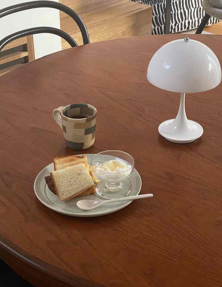 温かみのあるブラウンの木製ダイニングルーム、モダンな朝食シーンにセラミック皿とコーヒーマグが配置された雰囲気のあるインテリア