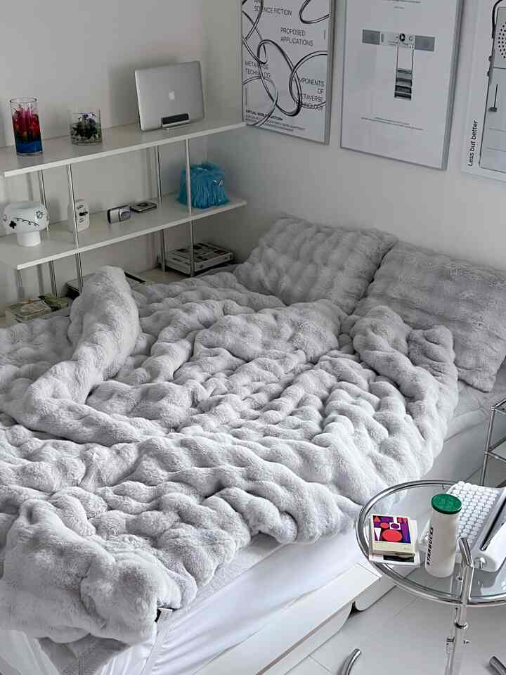 グレーと白の色調の寝室、大きなベッドにグレーの寝具、白い棚と壁にポスターが配置されたシンプルなインテリア