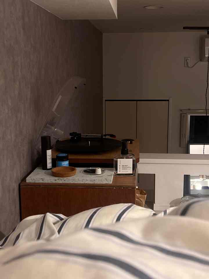 Loft bedroom space featuring brown wood tone furniture and gray textured walls, striped bedding in the foreground