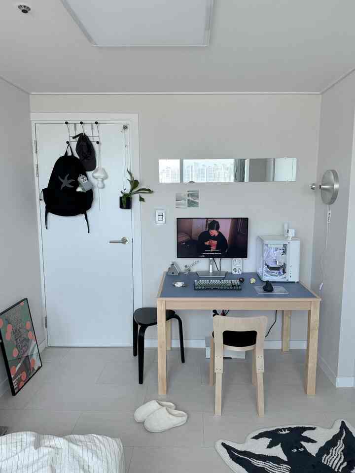 白とグレーのトーンが特徴のモダンでコンパクトなワンルームのホームオフィス、シンプルなデスクと椅子が配置されたインテリア