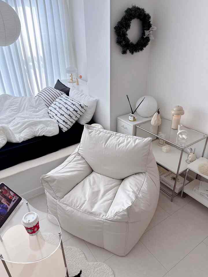 Bright white-toned bedroom featuring a bean bag chair and neat bedding creating a cozy space