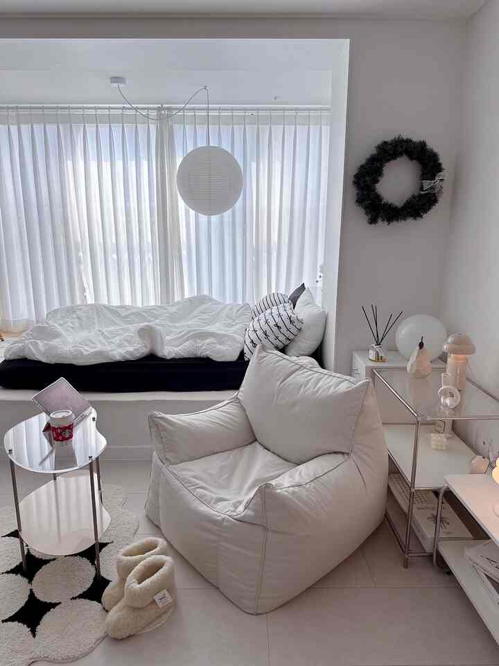 白を基調とした寝室、窓際にベッドと大きなビーズクッションが配置されたモダンなインテリア